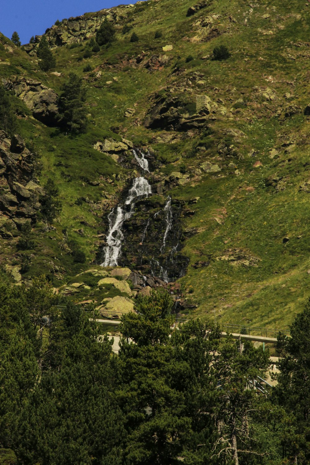 una ladera de montaña con una cascada en medio de ella