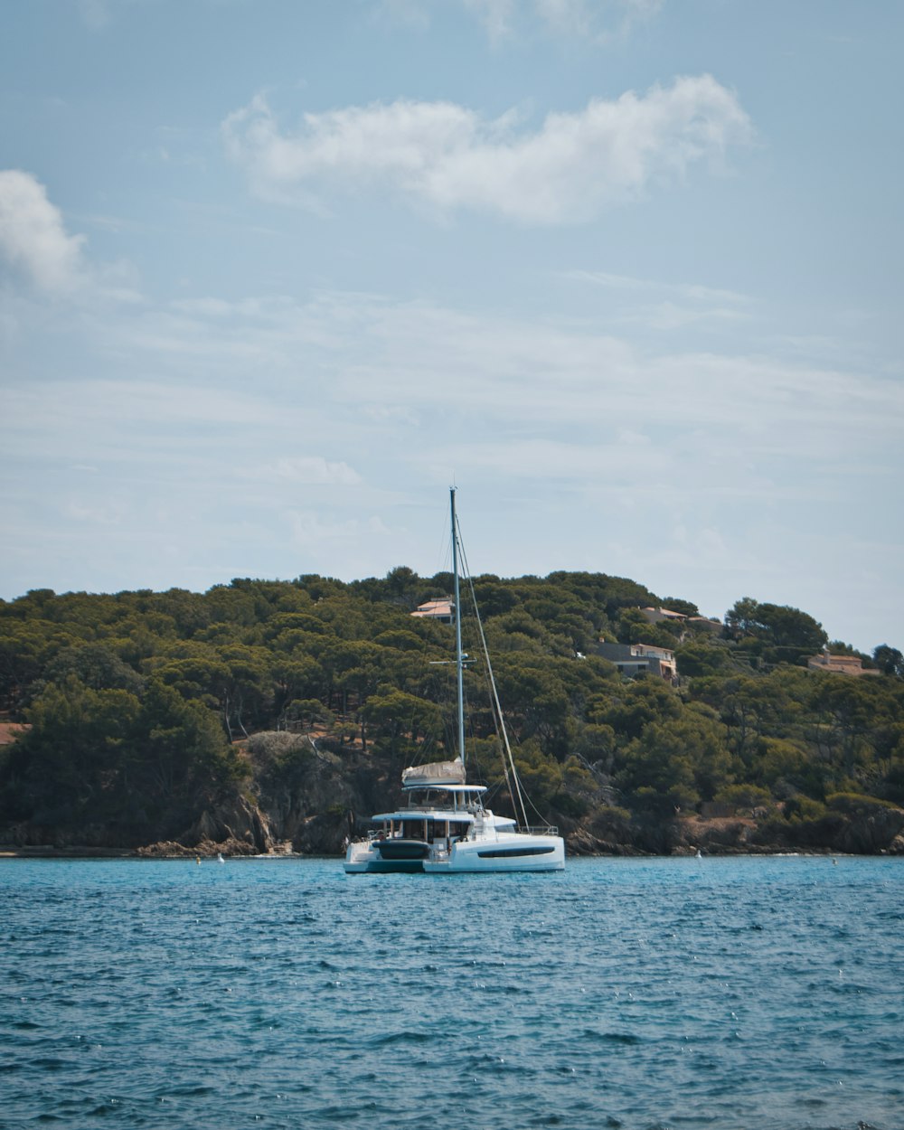 a sailboat in a body of water with a hill in the background