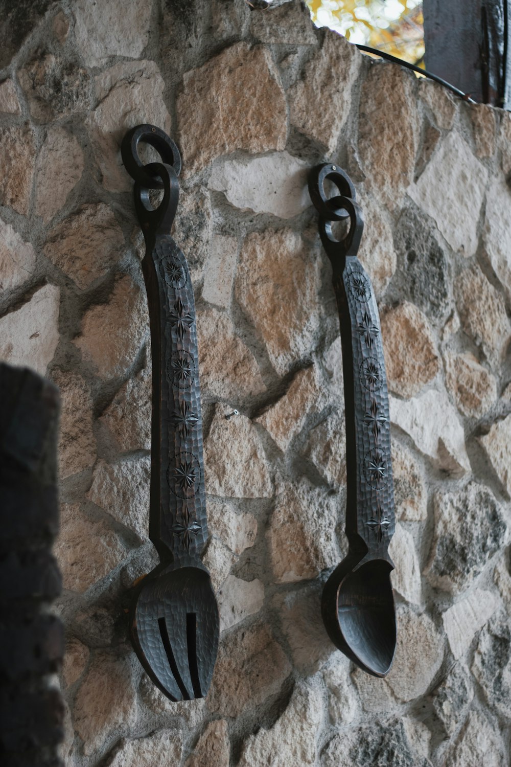 a couple of spoons hanging on a stone wall
