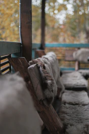 Warm wool throws folded on a rustic wooden bench.
