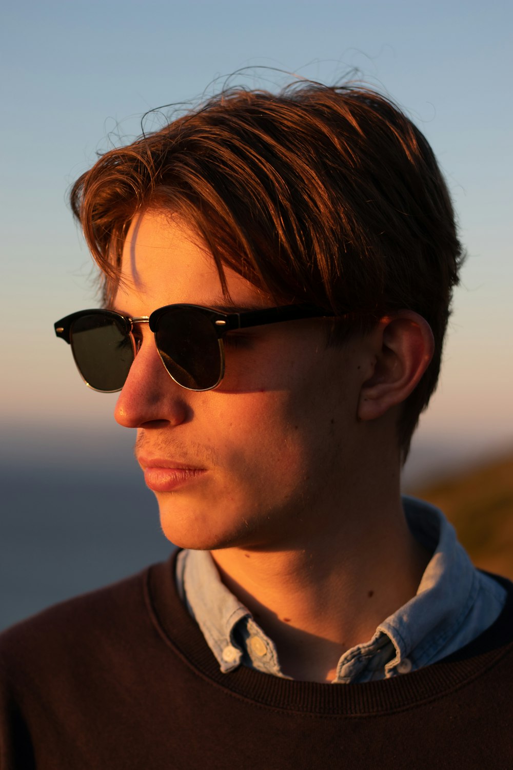 a young man wearing sunglasses looking off into the distance