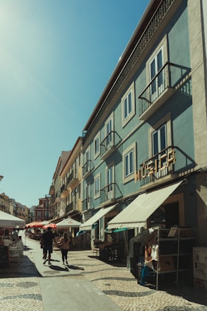 A lively street scene in Paperino with locals chatting and colorful buildings under a bright sky.