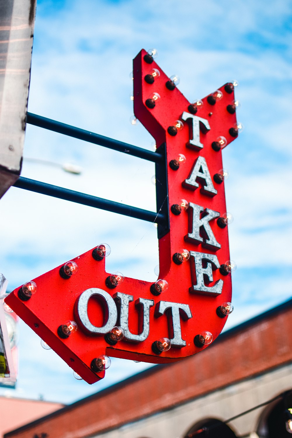 a red take out sign hanging from the side of a building