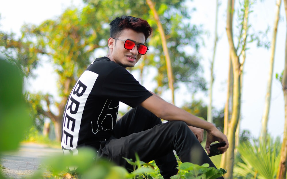 a man wearing red sunglasses sitting on the ground