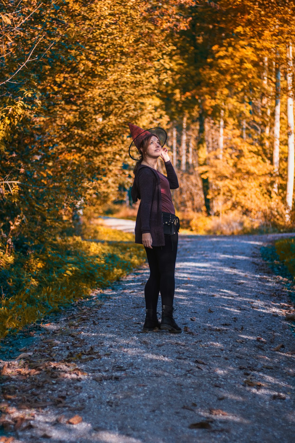 a woman standing on a dirt road in the woods