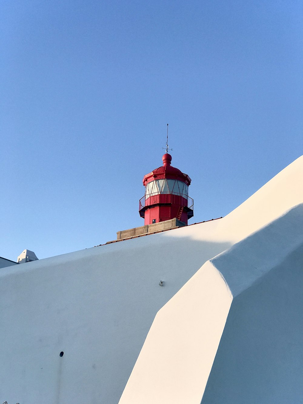a red and white lighthouse on top of a white wall