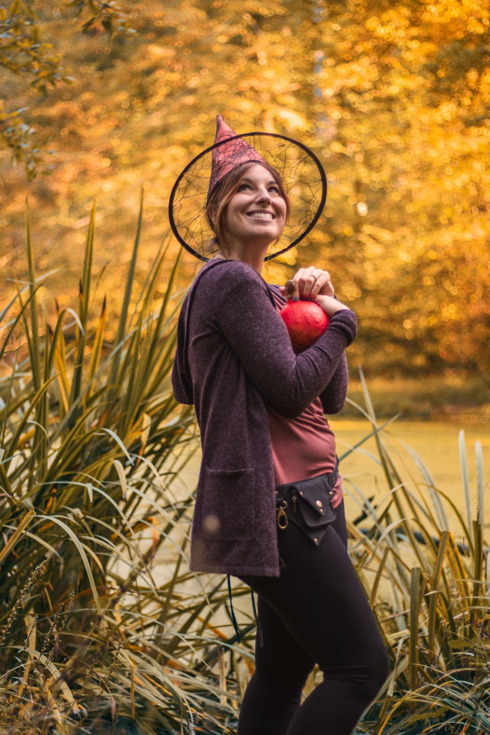 a woman wearing a hat and holding an apple