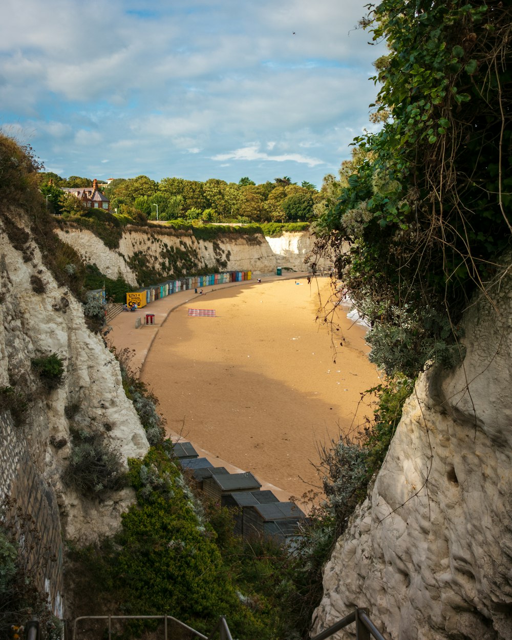 a sandy beach next to a cliff under a blue sky