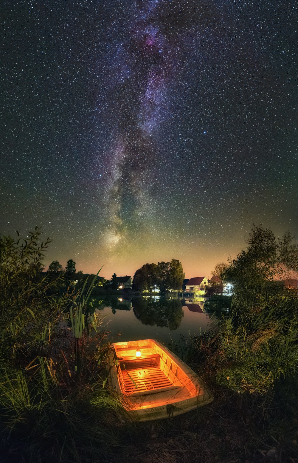 a boat sitting on top of a lake under a night sky