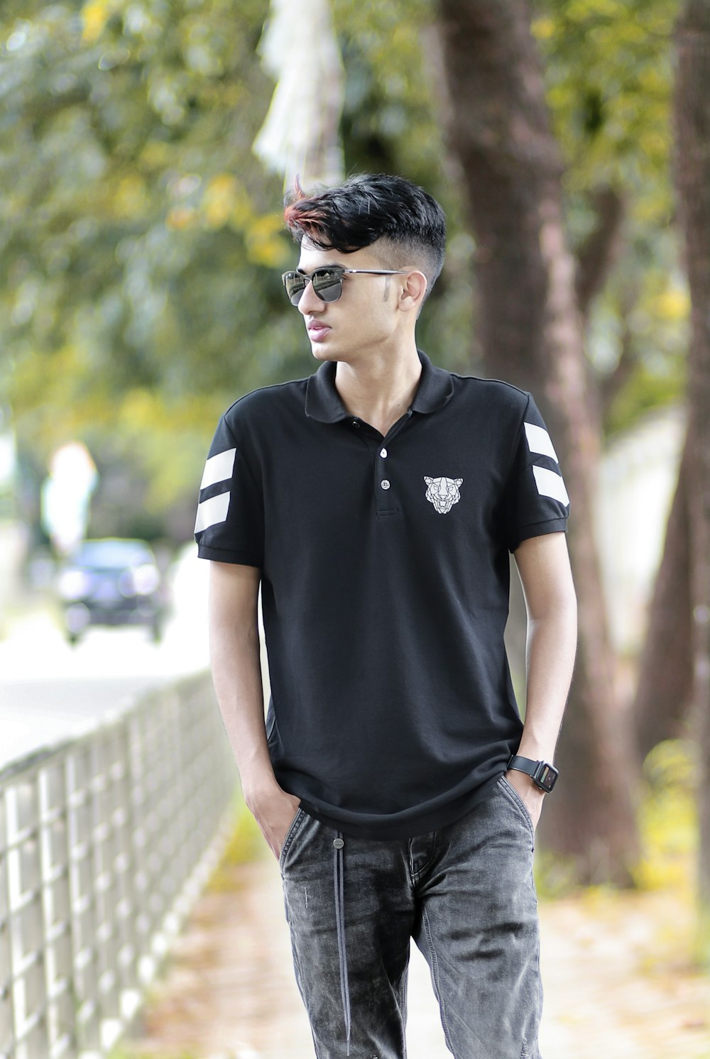 a man standing on a sidewalk wearing a black shirt