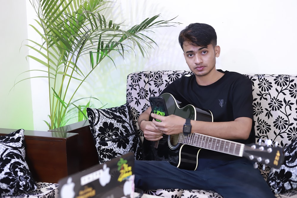a man sitting on a couch playing a guitar