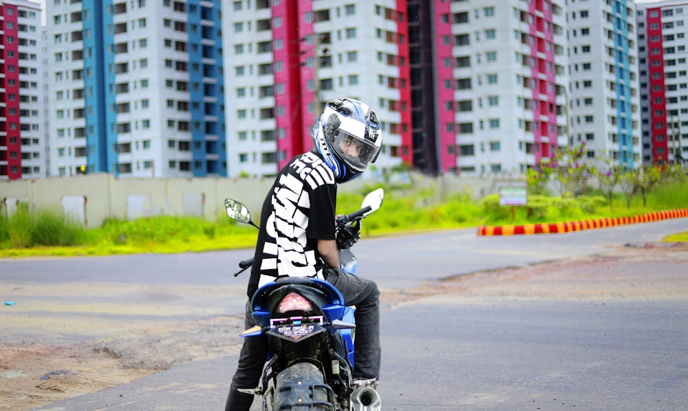 a man riding a motorcycle down a street next to tall buildings