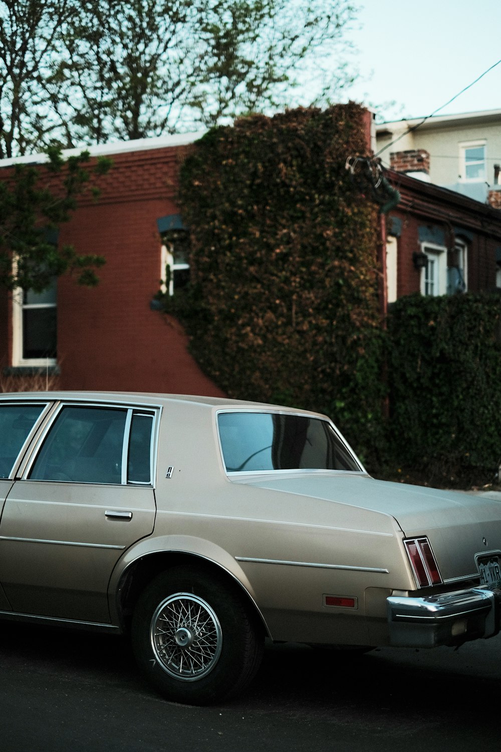 a tan station wagon parked in front of a house