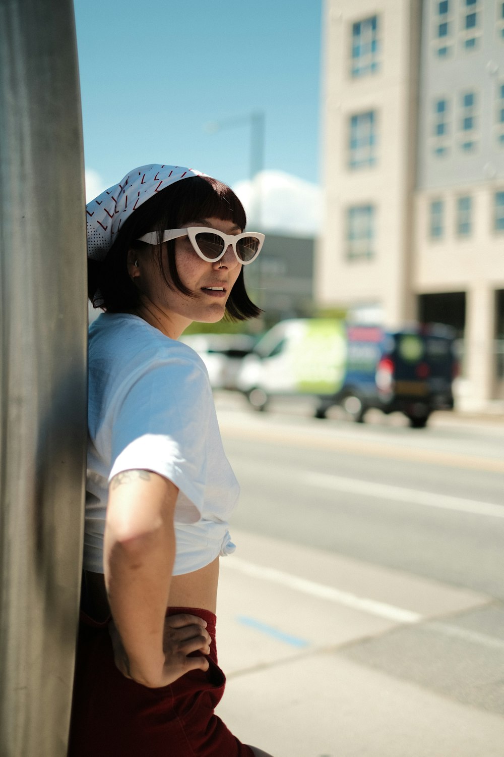 a woman wearing sunglasses leaning against a tire