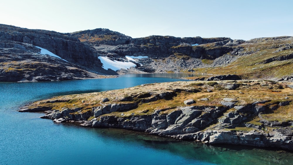 a body of water surrounded by mountains and grass