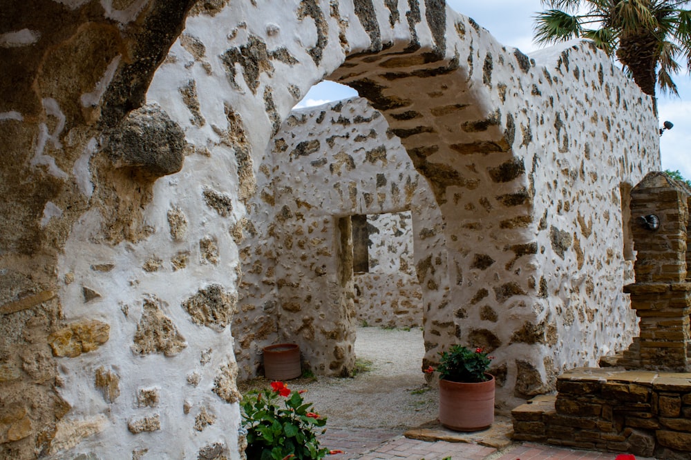 a stone building with a stone arch and potted plants