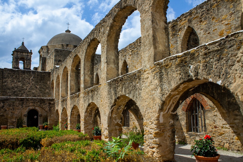 a stone building with arches and a clock tower in the background