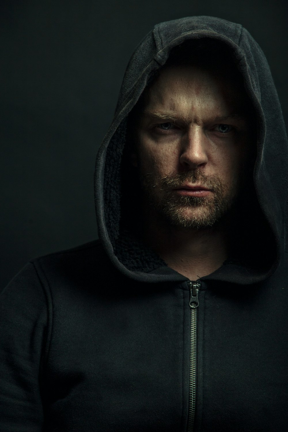 a man in a black hoodie looking at the camera