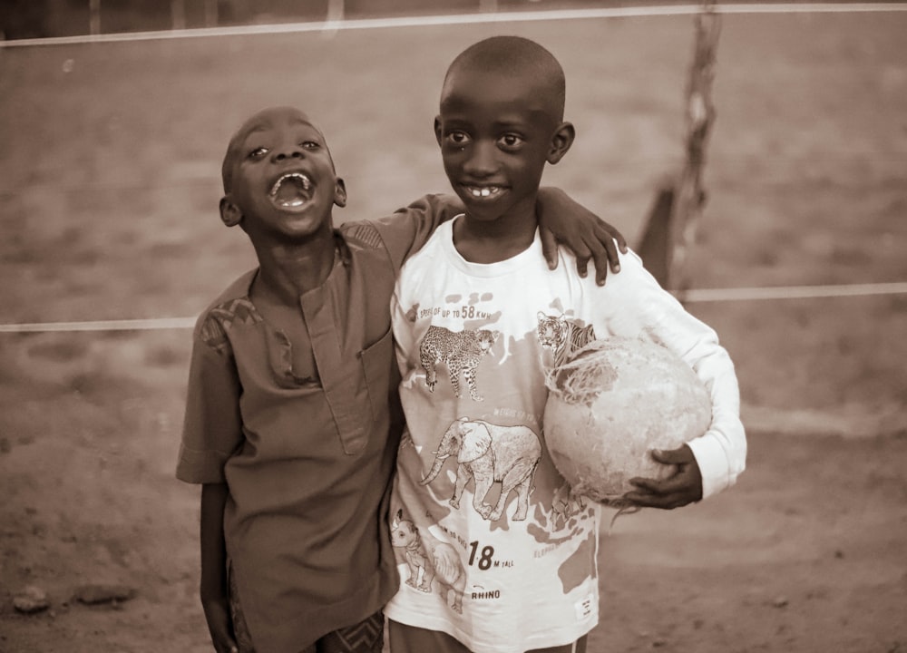 two young boys standing next to each other holding soccer balls