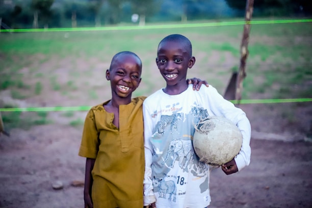 A smiling child playing soccer in a community field with friends.