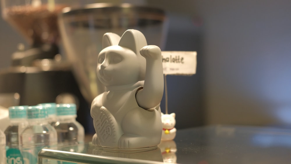 a white cat figurine sitting on top of a counter