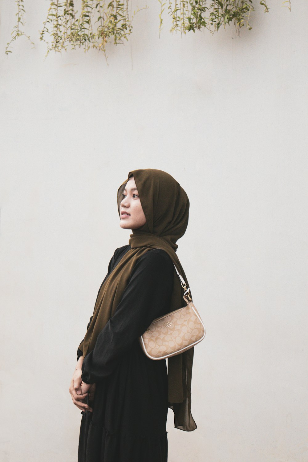 a woman wearing a hijab and carrying a purse