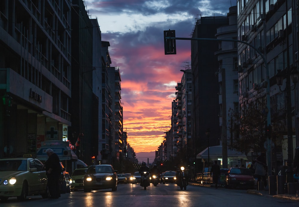 a city street filled with lots of traffic under a colorful sky