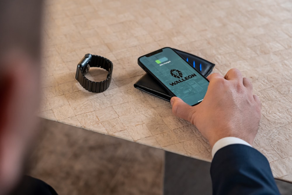 a man holding a smart phone next to a smart watch