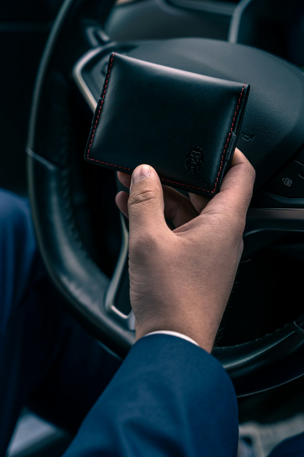 a person holding a wallet while driving a car