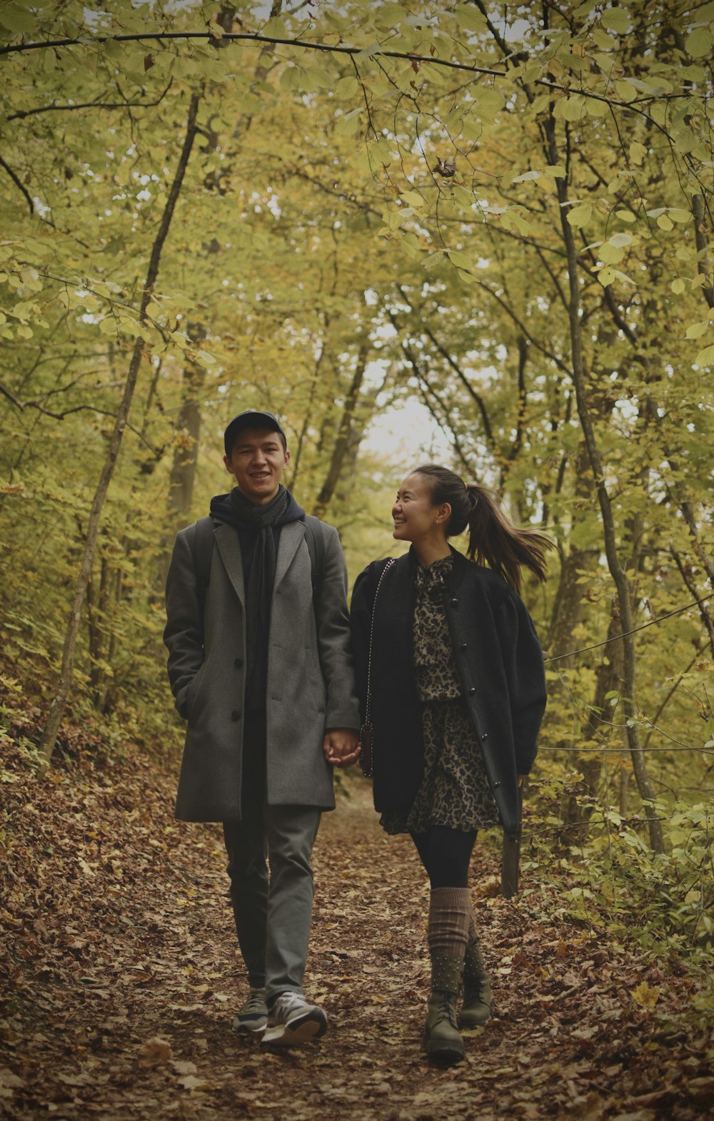a man and a woman walking down a path in the woods