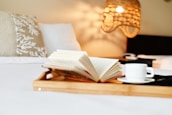 An open book resting on a bedside table with a warm lamp casting a cozy glow.