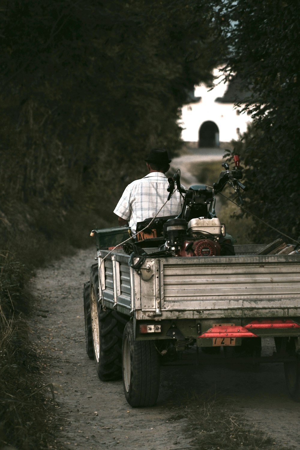 a man riding on the back of a truck down a dirt road