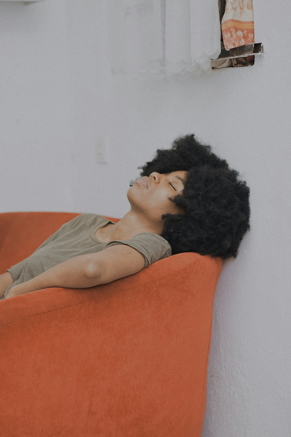 a woman laying on top of an orange couch