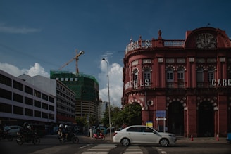 a white car driving down a street next to tall buildings