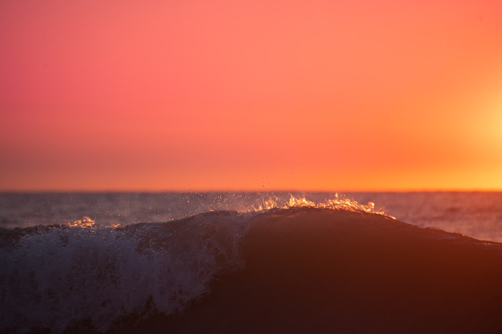 a person riding a surfboard on a wave at sunset