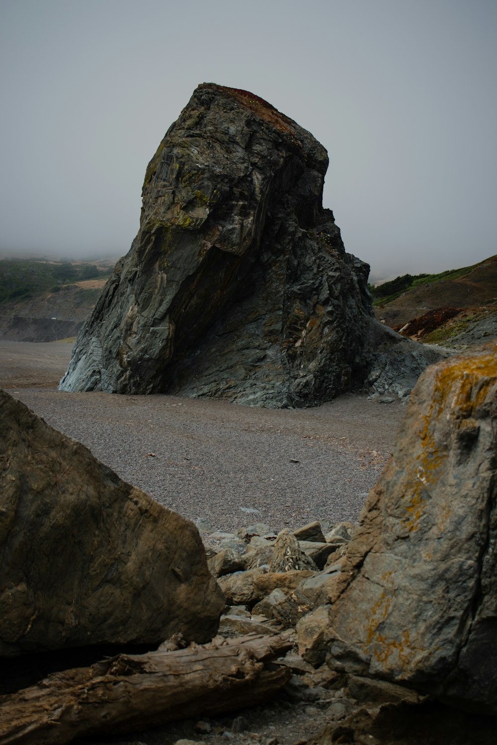 a large rock sitting on top of a sandy beach