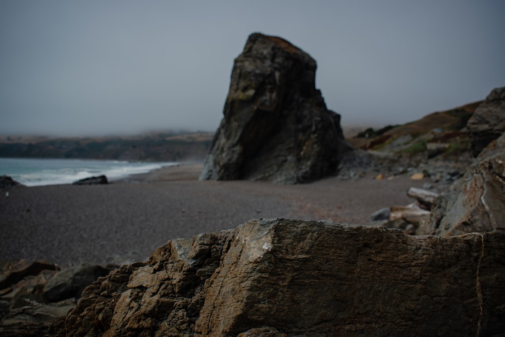 a rock formation on a beach with a body of water in the background