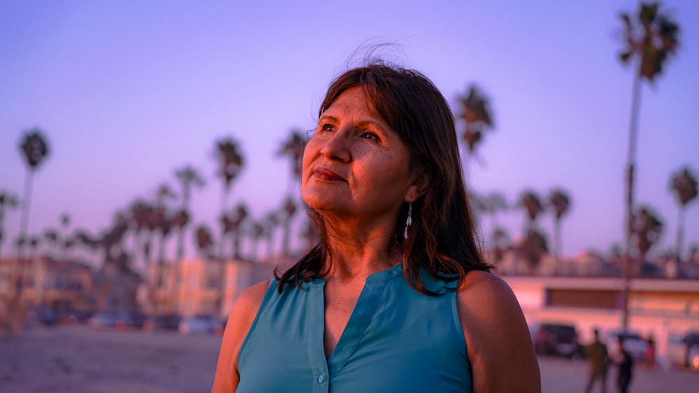 a woman in a blue top standing on a beach