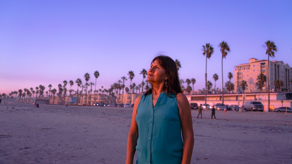 a woman standing on a beach next to palm trees