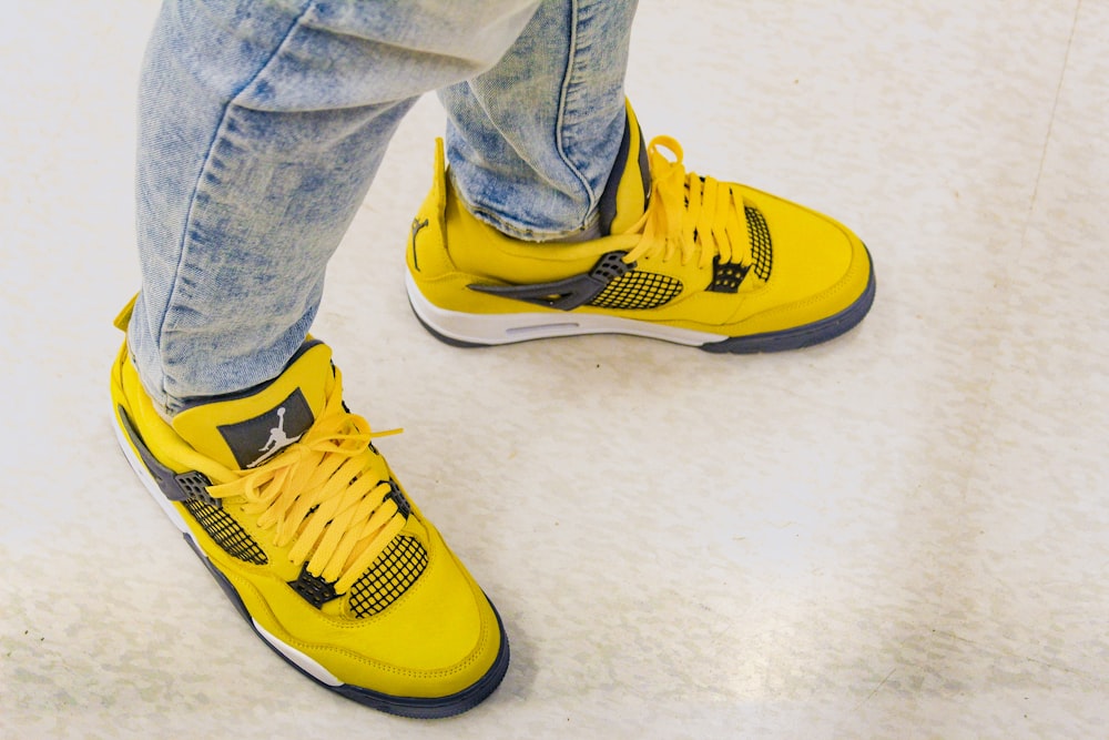 a pair of jeans and yellow sneakers on a person's feet