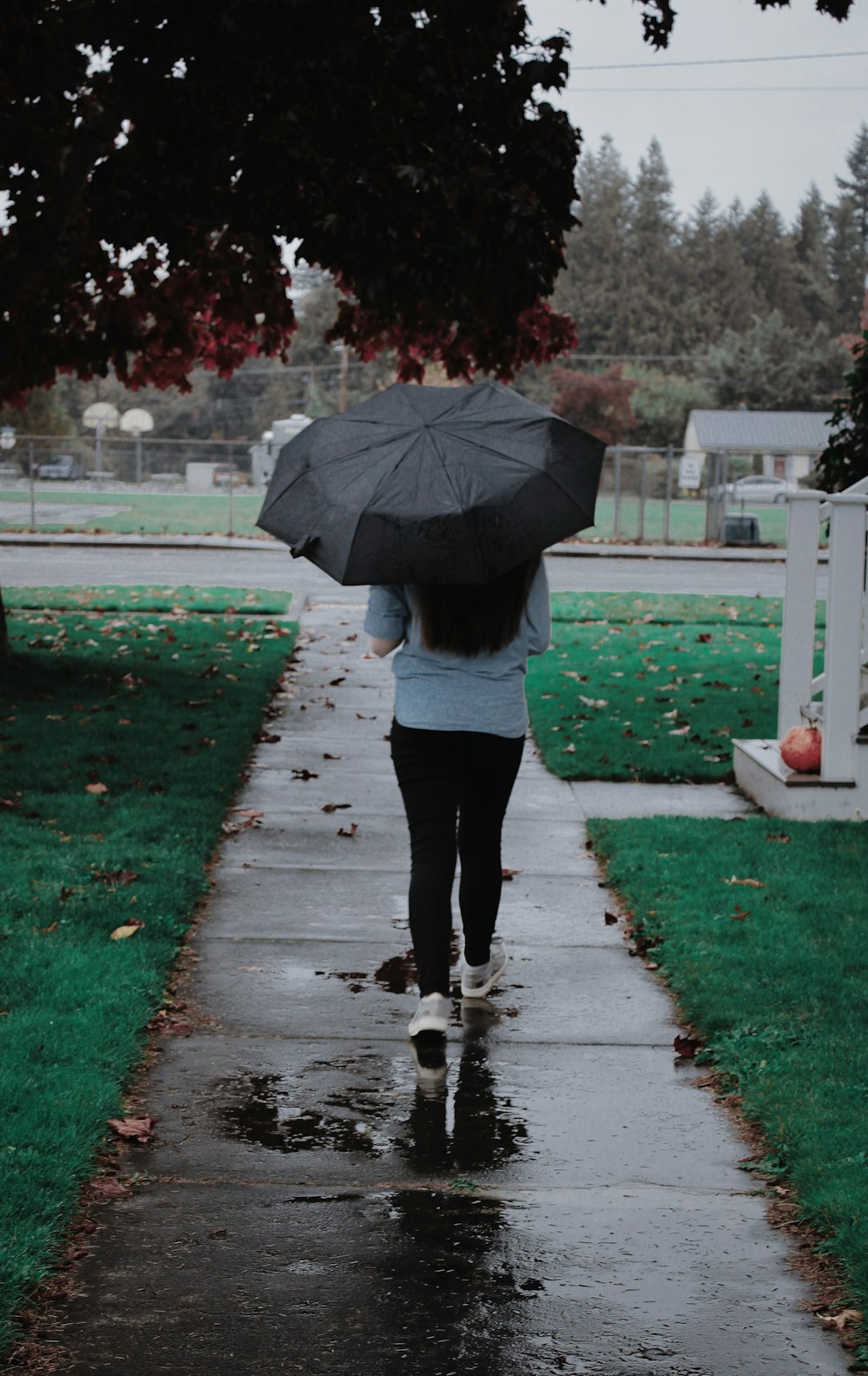 a woman walking down a sidewalk holding an umbrella