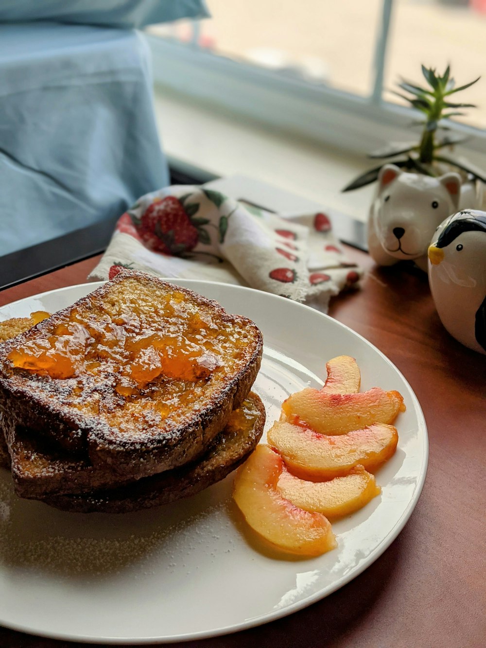 a white plate topped with french toast and sliced peaches