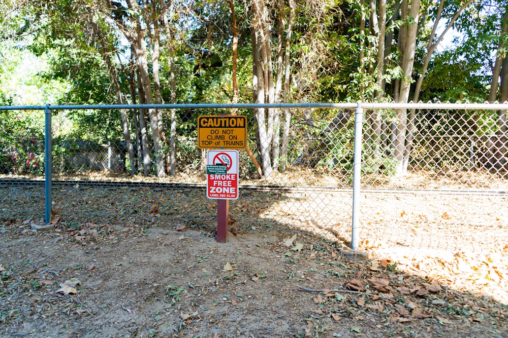 a caution sign in front of a chain link fence