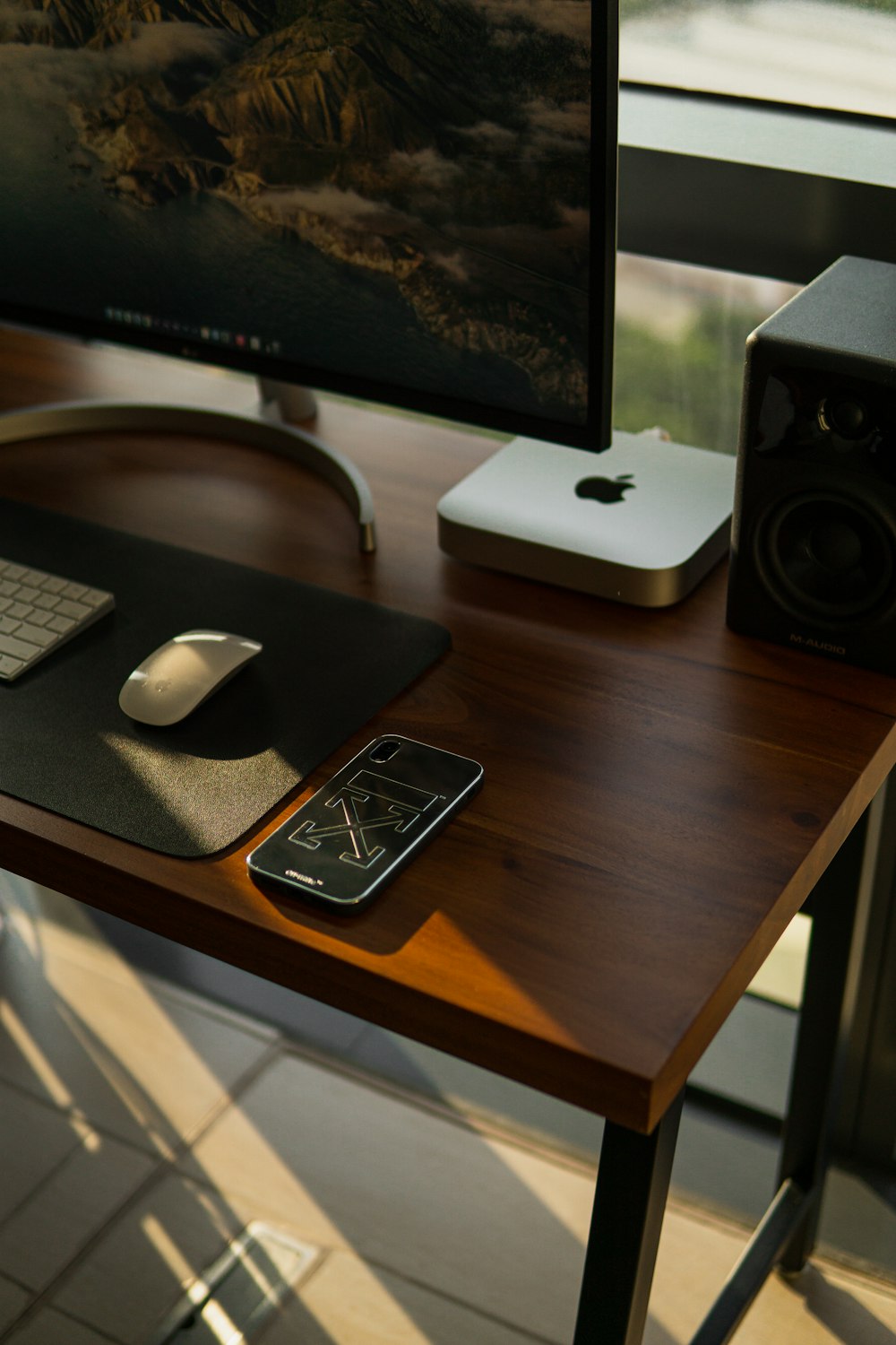 a computer monitor, keyboard, mouse and cell phone on a desk