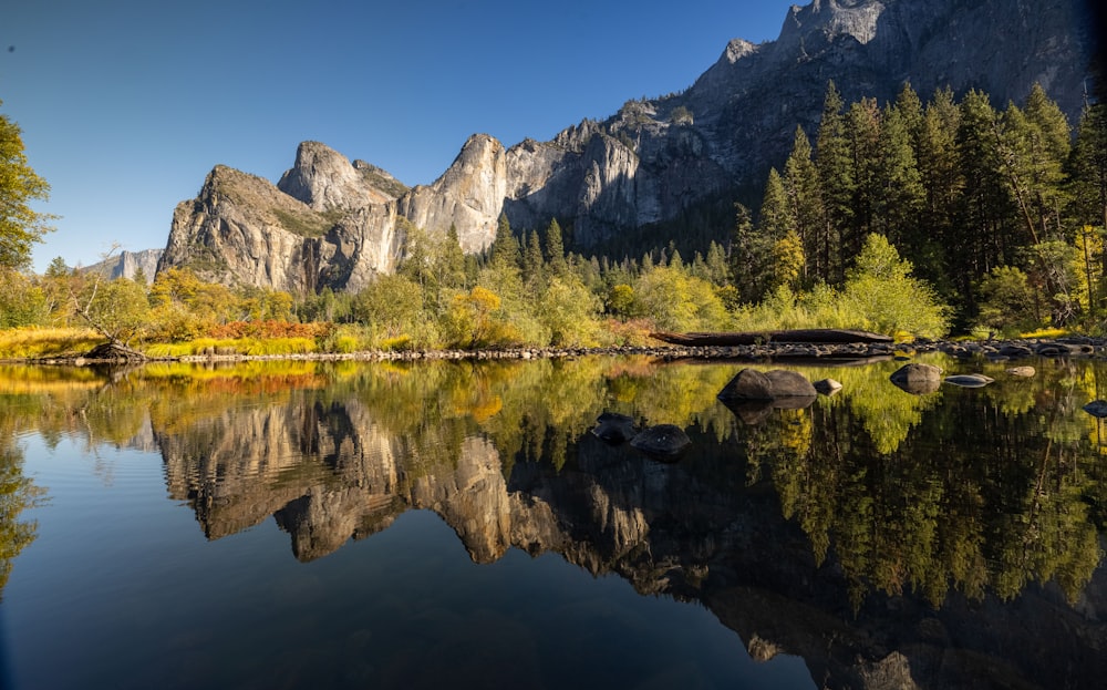 a mountain range is reflected in the still water of a lake