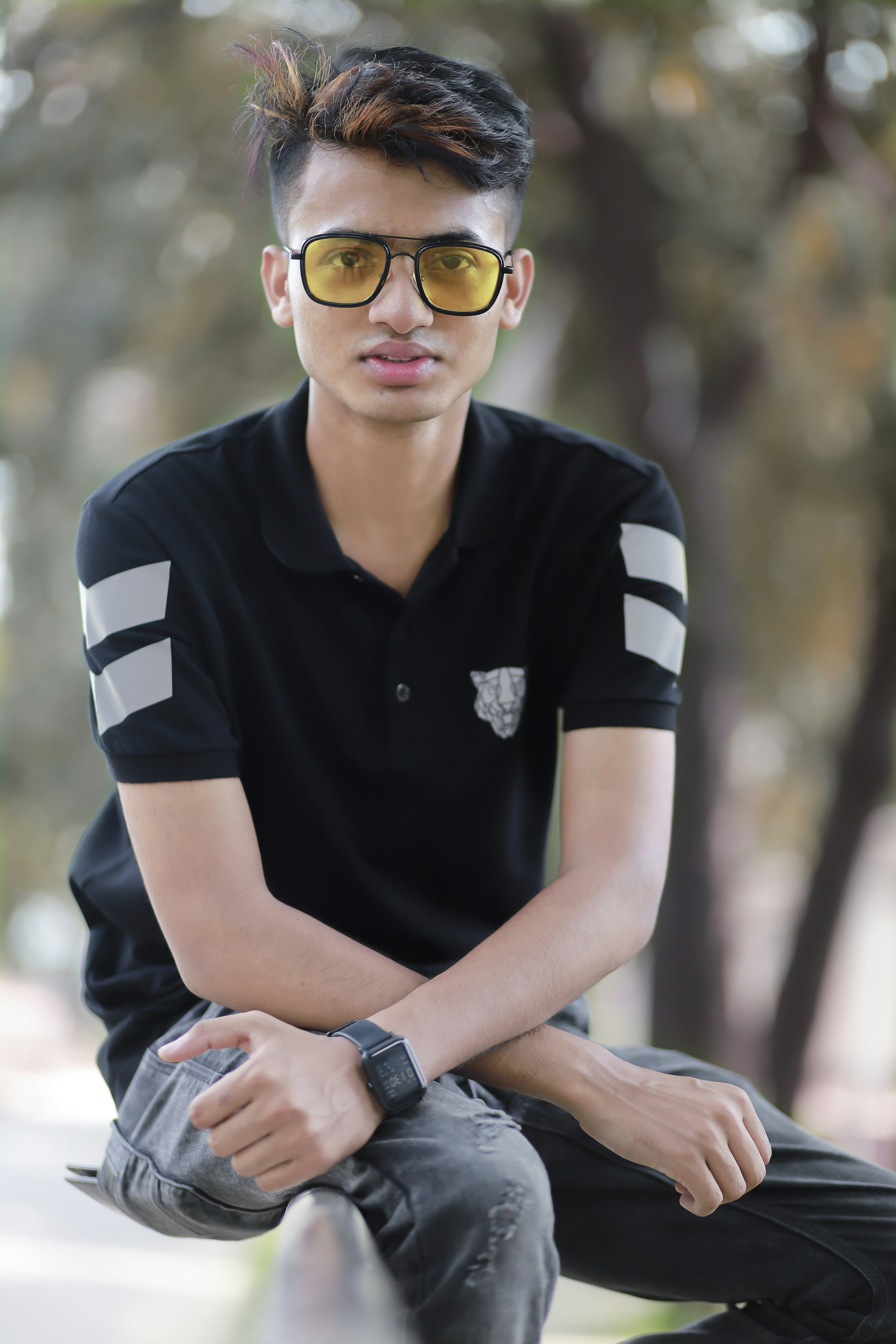 a young man wearing sunglasses sitting on a bench