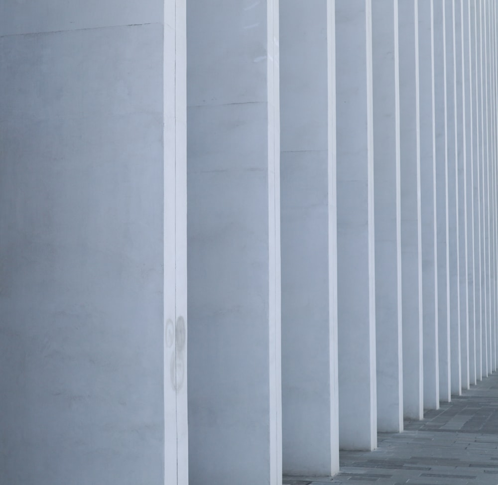 a woman walking down a sidewalk next to tall white pillars