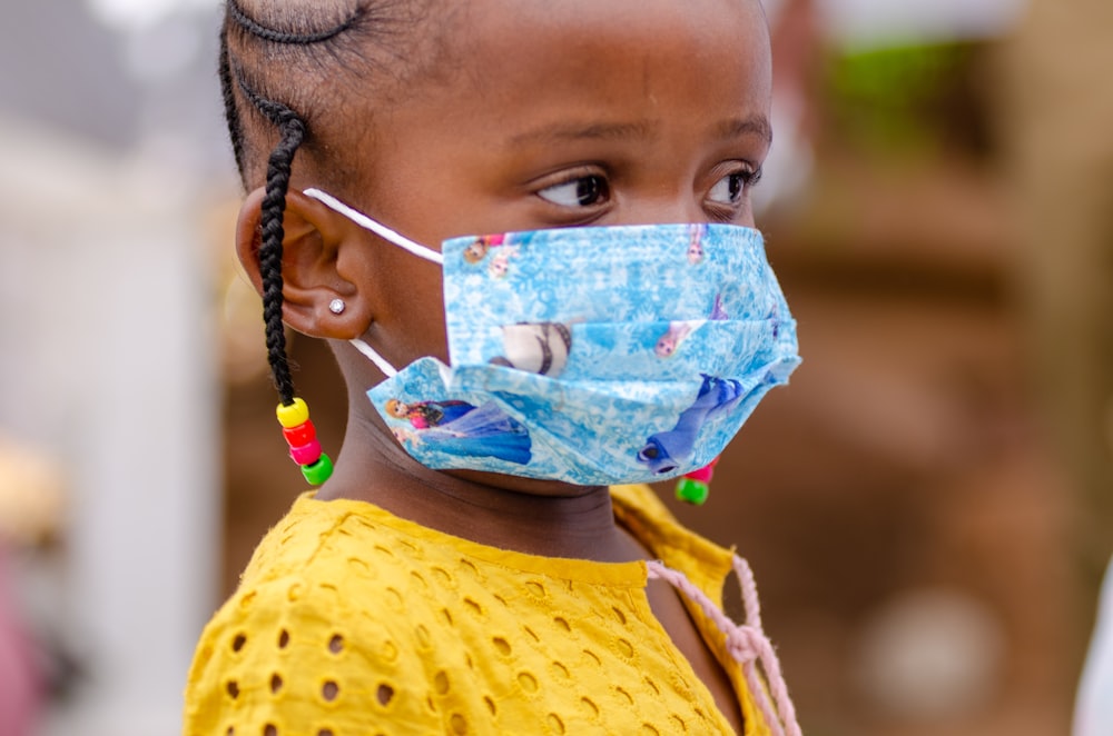 a little girl wearing a face mask and braids