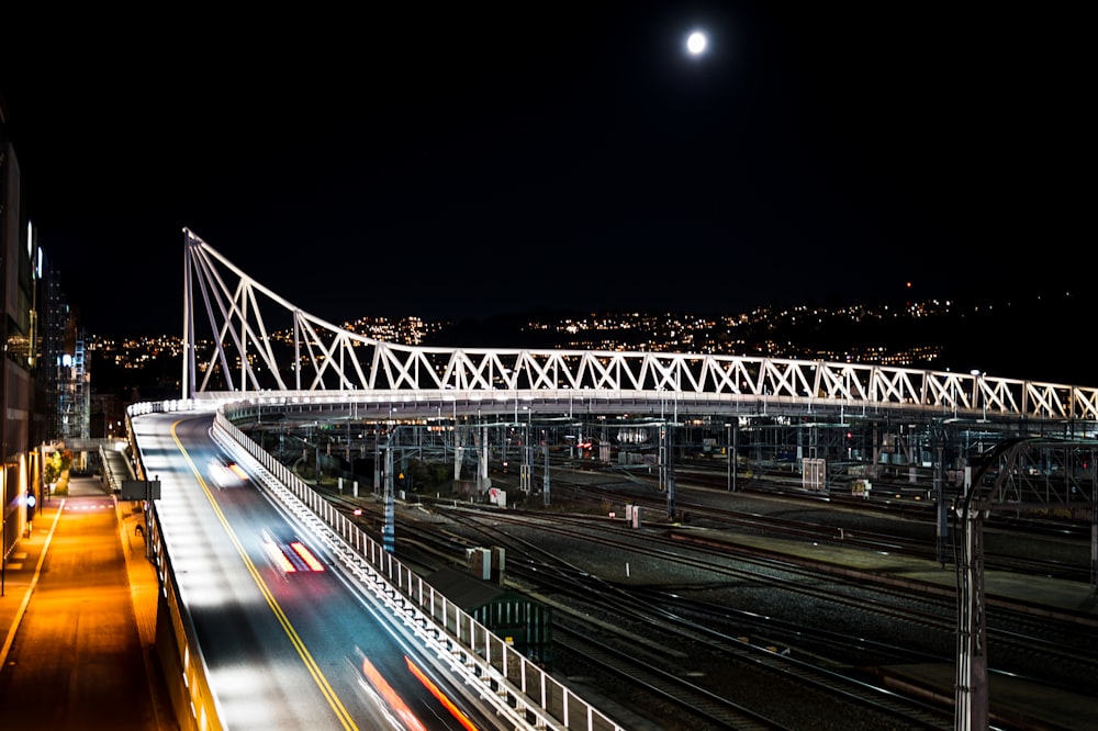 a night time view of a city with a bridge and train tracks