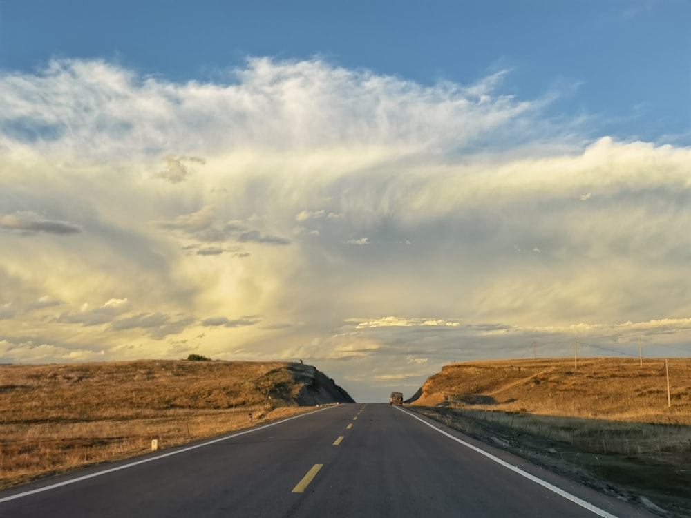 a long road with a sky filled with clouds